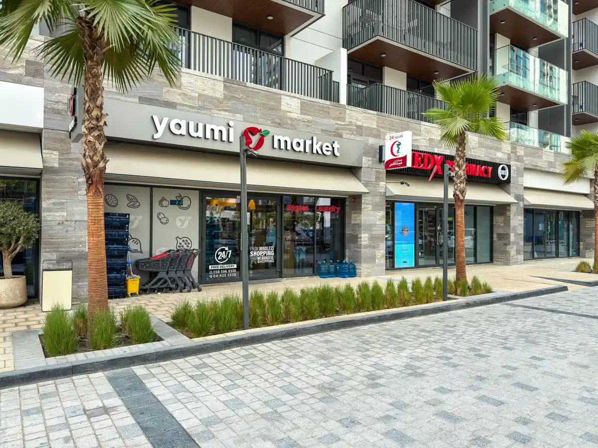 Retail street at Crest Grande, Sobha Hartland: supermarket, pharmacy, salon and cafe within the building, daylight