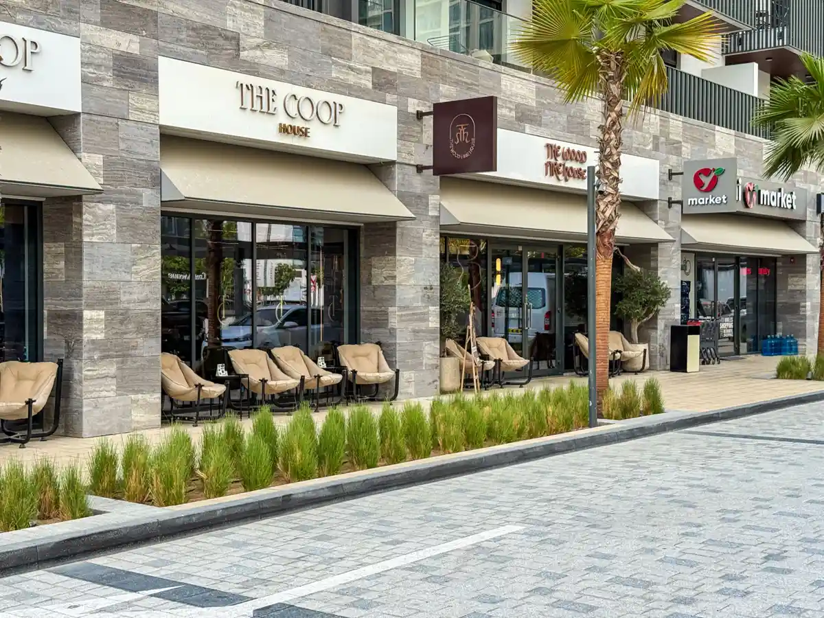 Retail street at Crest Grande, Sobha Hartland: supermarket, pharmacy, salon and cafe within the building, daylight
