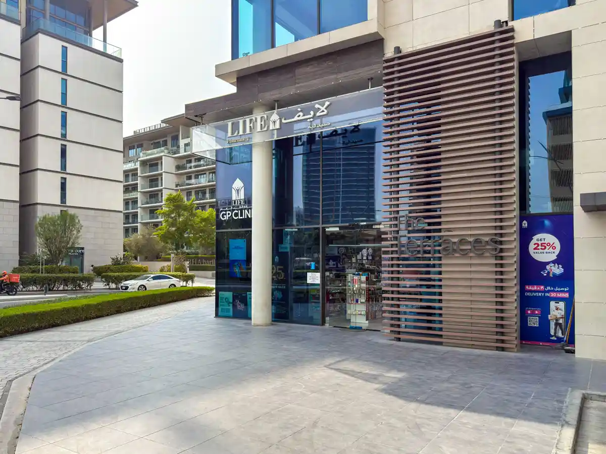 Retail street at Crest Grande, Sobha Hartland: supermarket, pharmacy, salon and cafe within the building, daylight