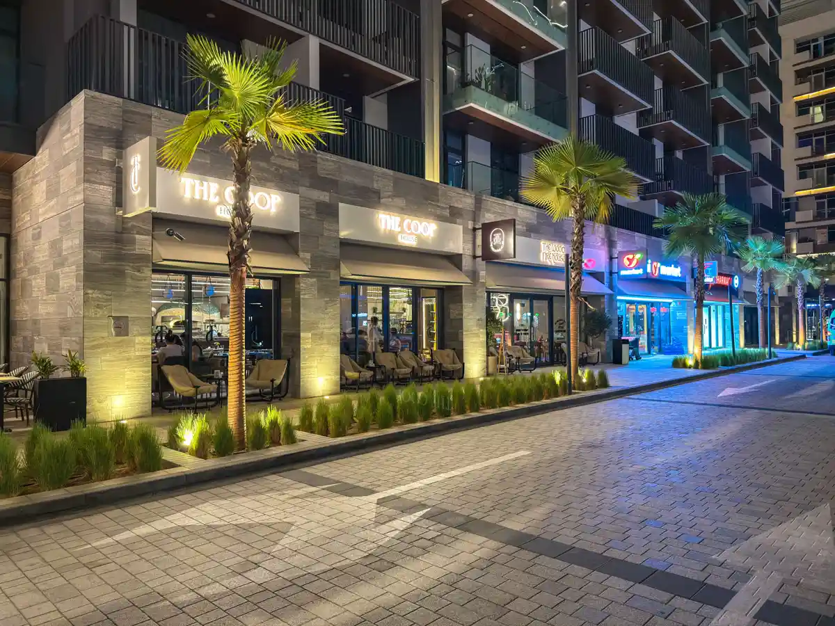 Retail street at Crest Grande, Sobha Hartland at night: The Coop cafe and shops