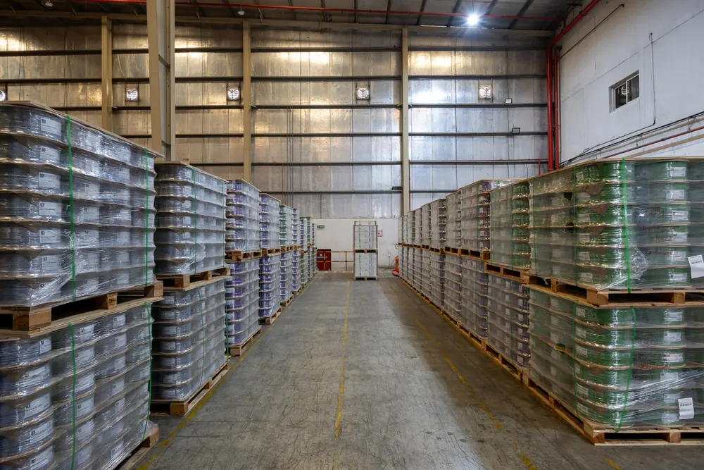 Wide aisle between pallets of wrapped B3 International cable drums at the distribution warehouse in Jebel Ali, Dubai.