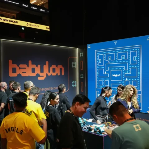 Visitors crowding the Babylon booth on the exhibition floor. Photographed by MRPS for Eventflare at Binance Blockchain Week 2025, Coca-Cola Arena, Dubai.