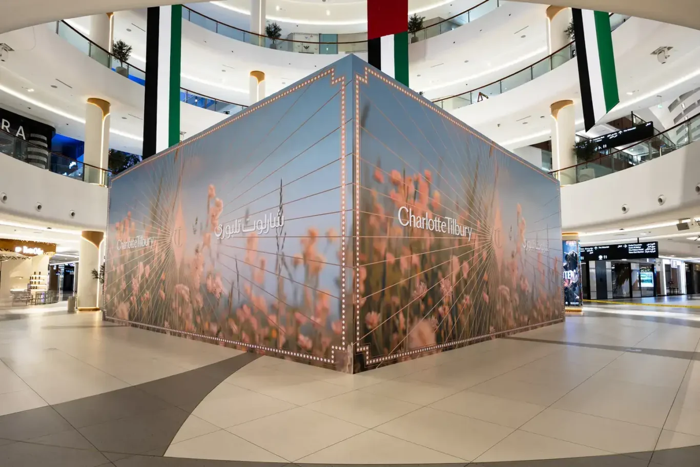 Corner view of a freestanding Hoarding by Lomax mall hoarding with Charlotte Tilbury floral graphics in the atrium of The Dubai Mall.