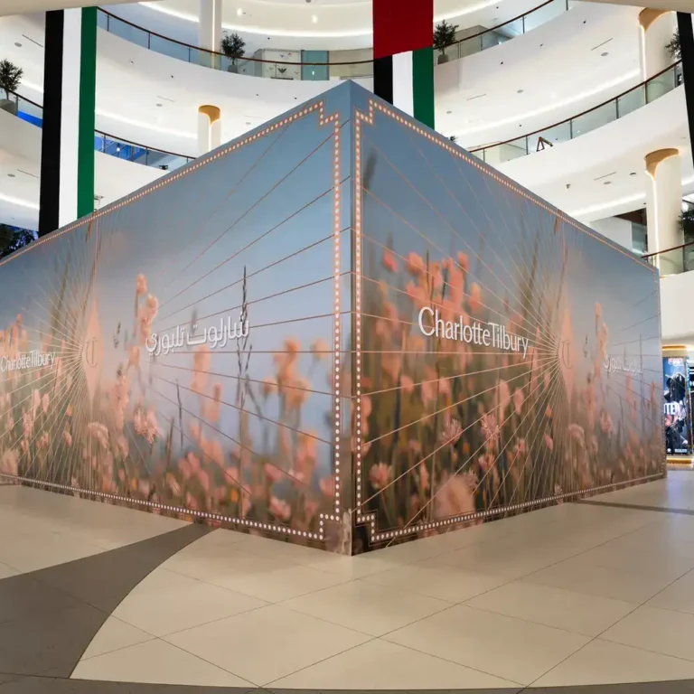 Corner view of a freestanding Hoarding by Lomax mall hoarding with Charlotte Tilbury floral graphics in the atrium of The Dubai Mall.
