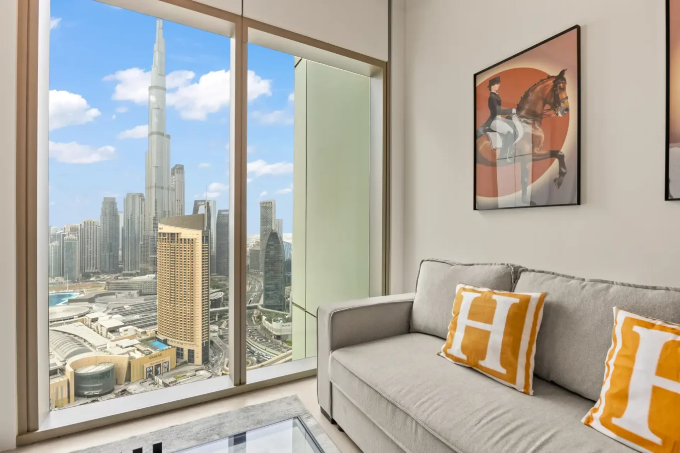 Living room with floor to ceiling windows and a direct Burj Khalifa view in daylight. Day, twilight and night Airbnb photography by MRPS for Vista Haus Holiday Homes in Downtown Dubai.