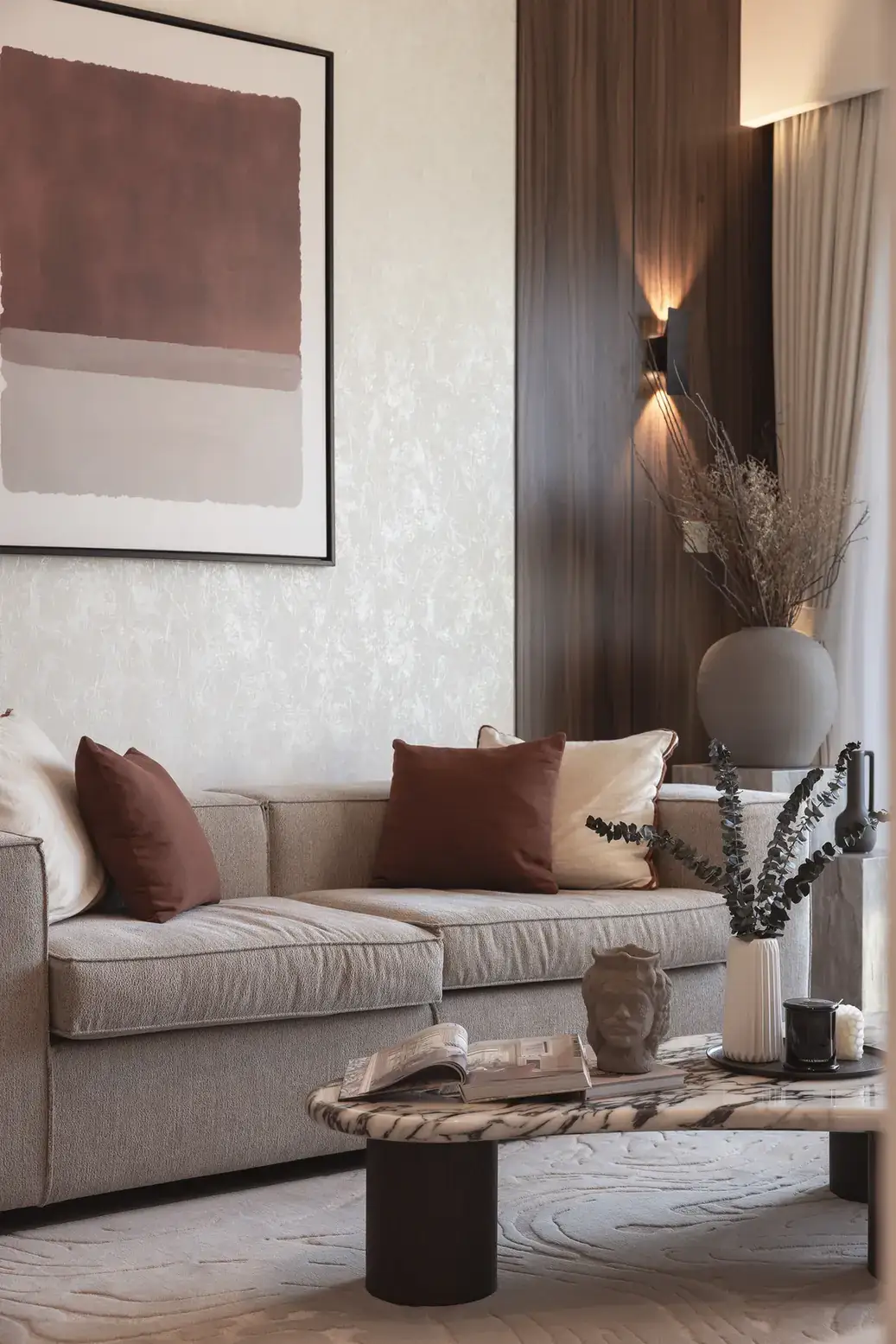 Japandi living room with beige sofa, rust cushions, abstract wall art and wooden slat wall. Interior design photography for Aziza Home by MRPS in Dubai.