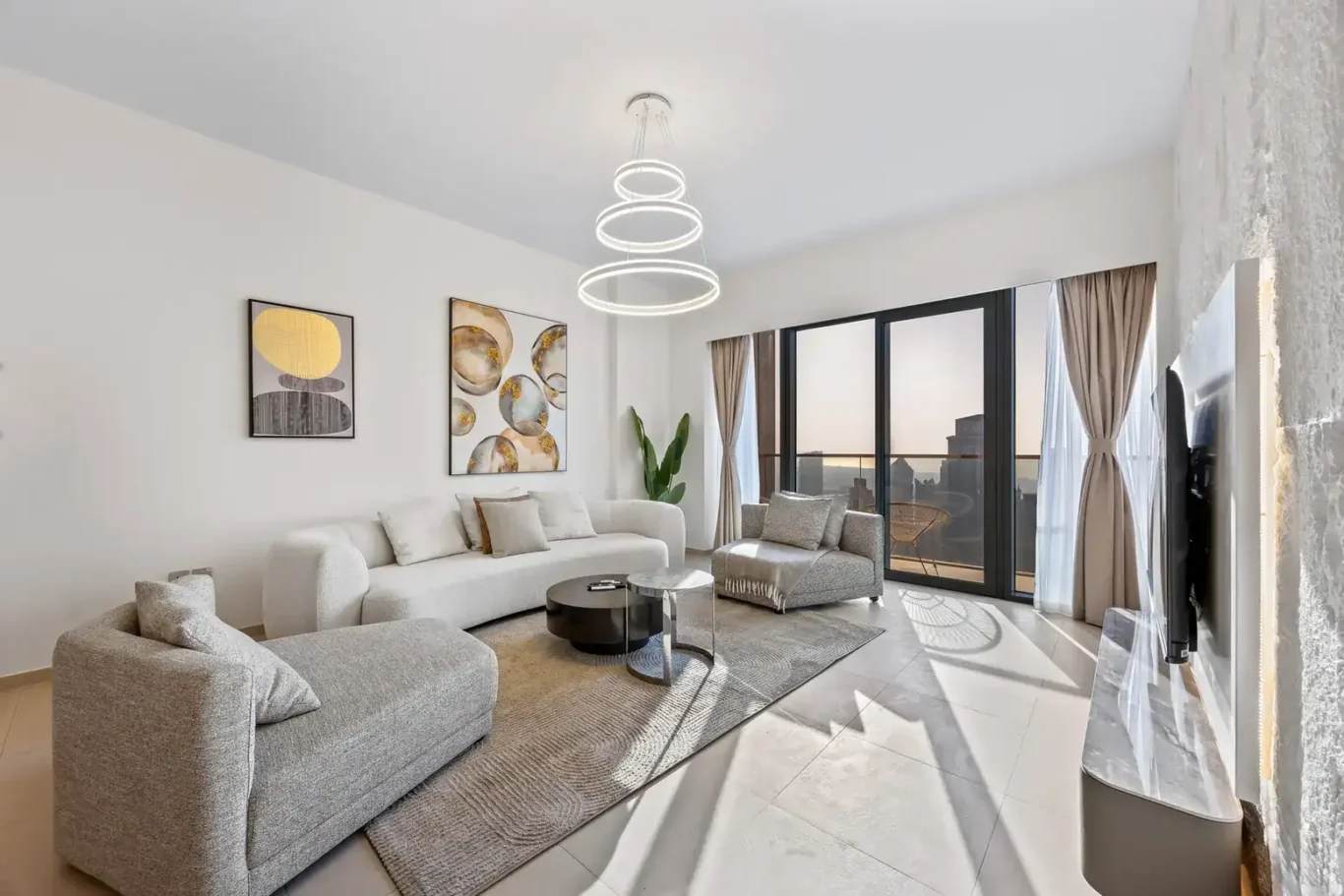 Bright living room with curved sofas, chandelier and floor to ceiling windows. Airbnb photography by MRPS for Solea Stay in Dubai.