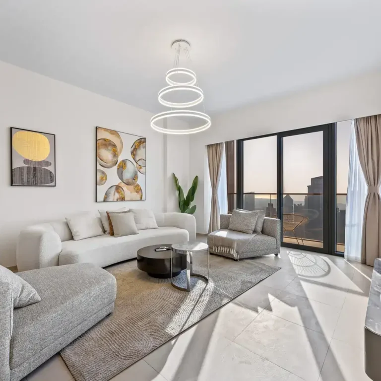 Bright living room with curved sofas, chandelier and floor to ceiling windows. Airbnb photography by MRPS for Solea Stay in Dubai.
