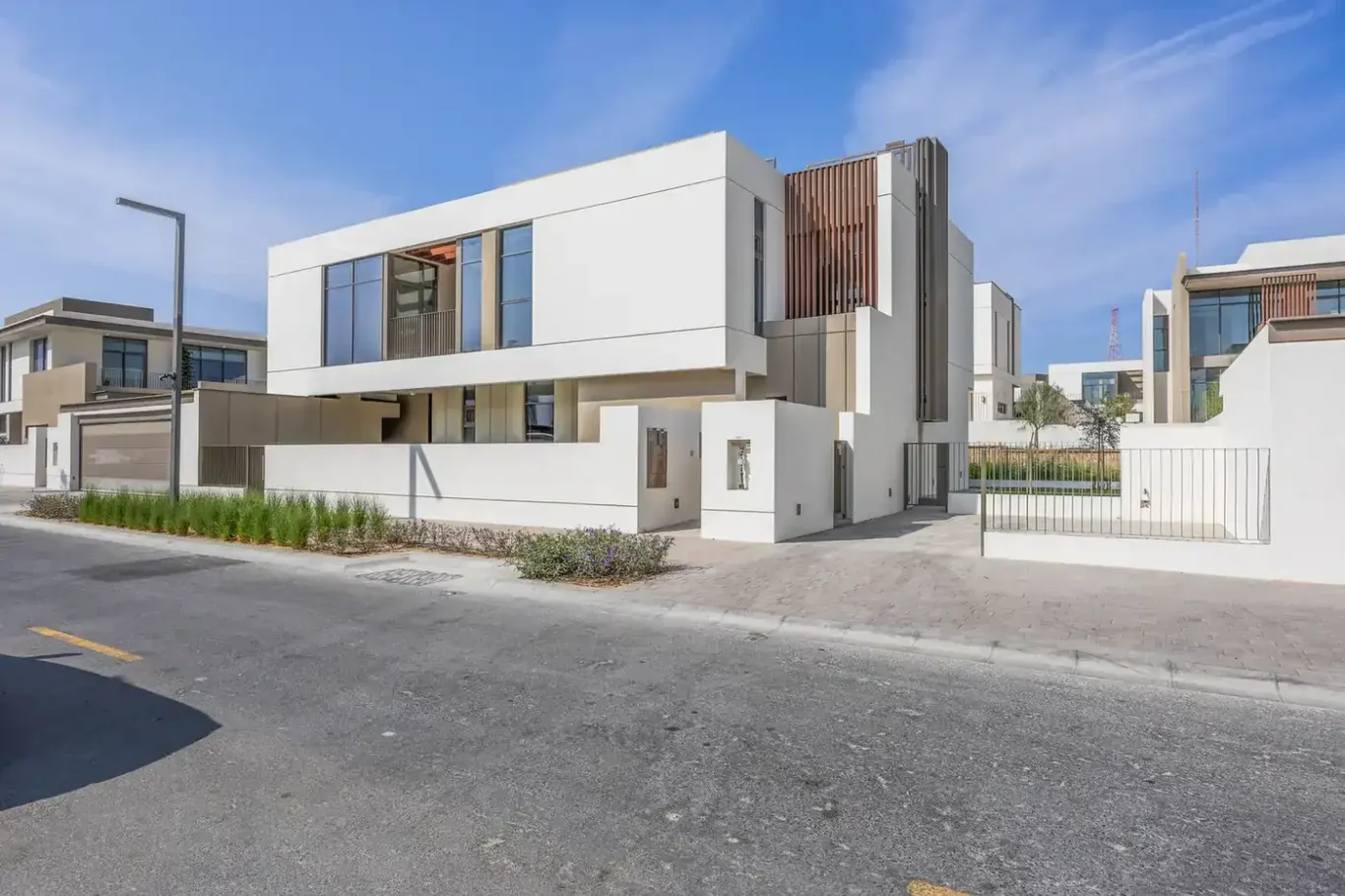 Front elevation of a brand new four bedroom villa in Tilal Al Furjan, white facade with timber accents. Villa photography by MRPS in Dubai for ELITE Property Brokerage.