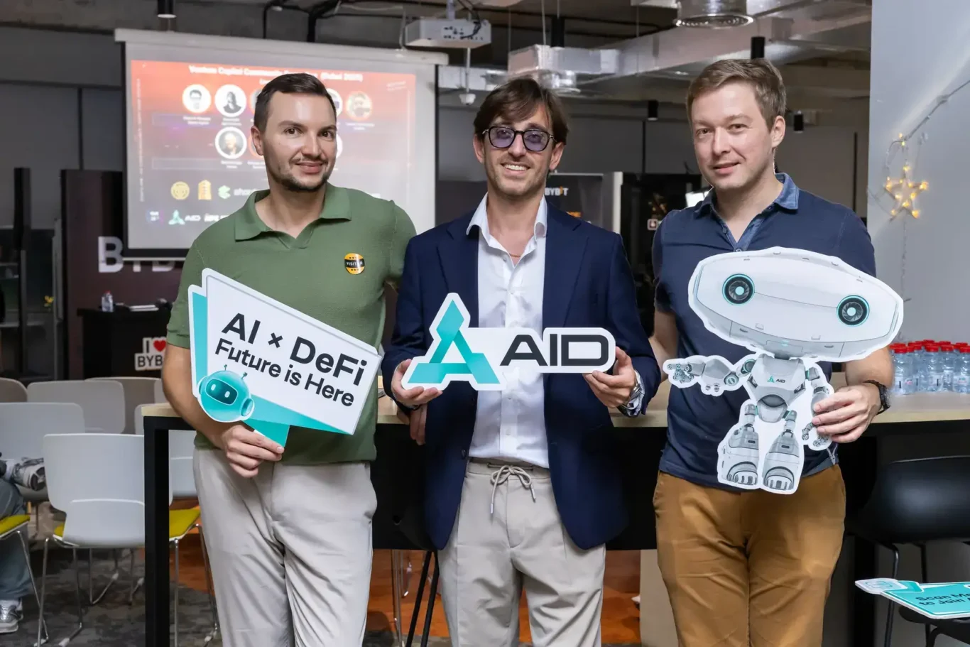 AID team holding AI x DeFi signs with the AID mascot. Event photography by MRPS at Blockchain Life 2025, Festival Arena, Dubai.