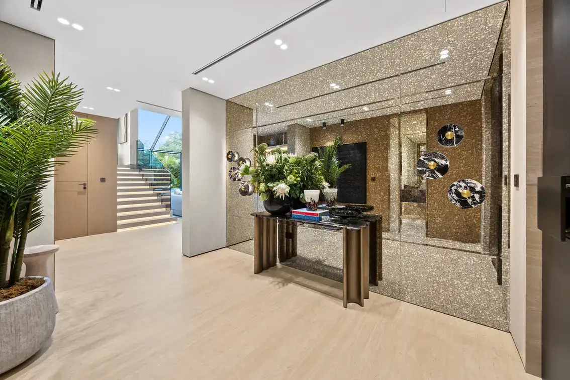 Entrance console with books and flowers in front of a decorative mirror wall, luxury villa in Jumeirah Islands, Dubai.