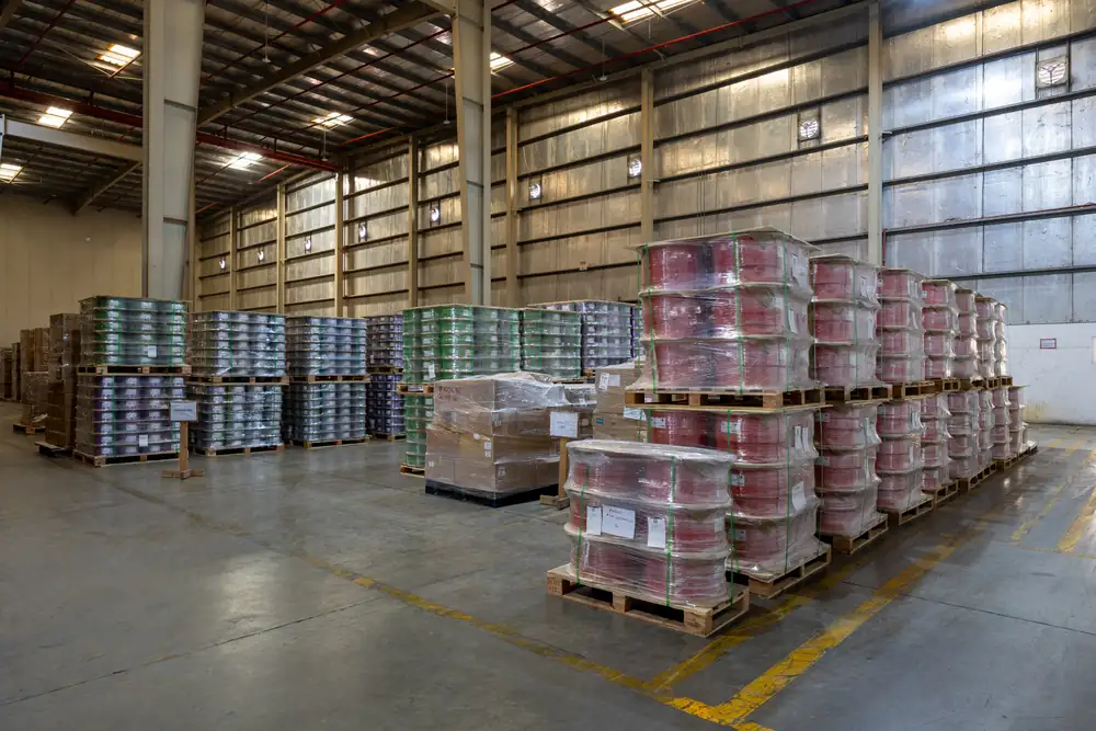 Warehouse floor at the B3 International cable distribution hub in Jebel Ali with stacked pallets of cable reels.