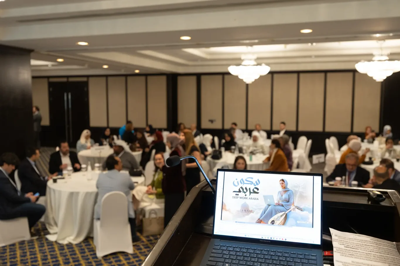 Ballroom full of educators at round tables with the bilArabi presentation on a laptop in the foreground. Corporate event photography by MRPS for My Arabic Publishing at Movenpick Grand Al Bustan, Dubai.
