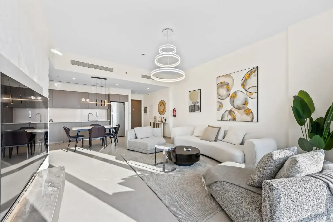 Open plan living room with grey sofas, round coffee table and dining area. Airbnb photography by MRPS for Solea Stay in Dubai.