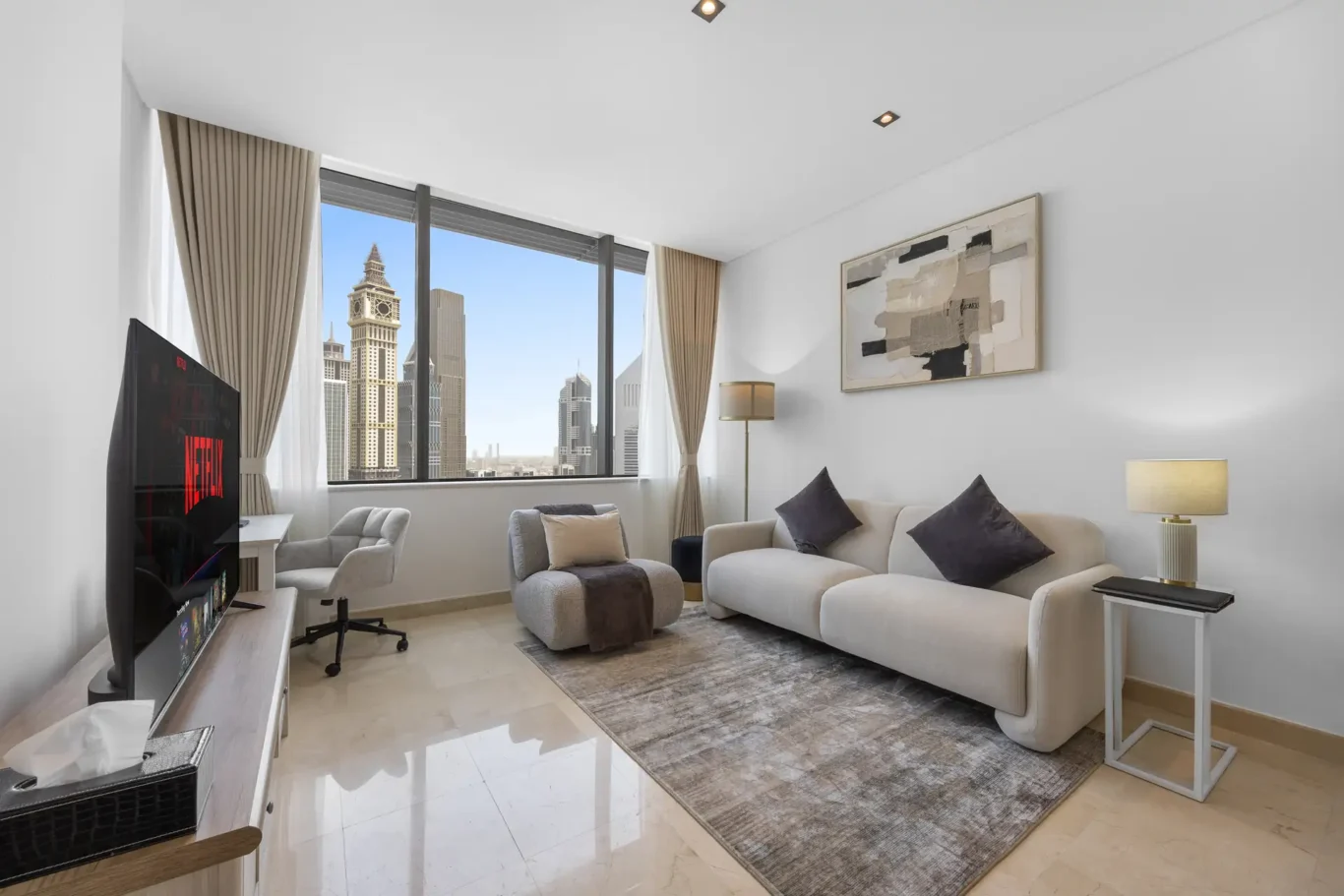 Living room with sofa, armchair and smart TV in a Your Stay Apartments one-bedroom at Sky Gardens, DIFC, Dubai.