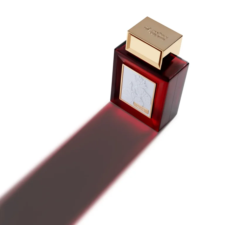 High-angle shot of the red Oud Elite Portrait perfume bottle casting a long red shadow across a white surface.