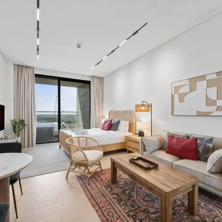 Wide view of the furnished studio with lounge, dining corner and bed in a XURU Stays studio at Trillionaire Residences by Binghatti, Business Bay, Dubai.