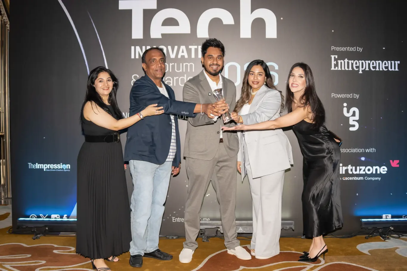 FundedNext team celebrating with the trophy in front of the awards backdrop. Event photography by MRPS for FundedNext at the Tech Innovation Awards 2026, Al Habtoor Palace, Dubai.