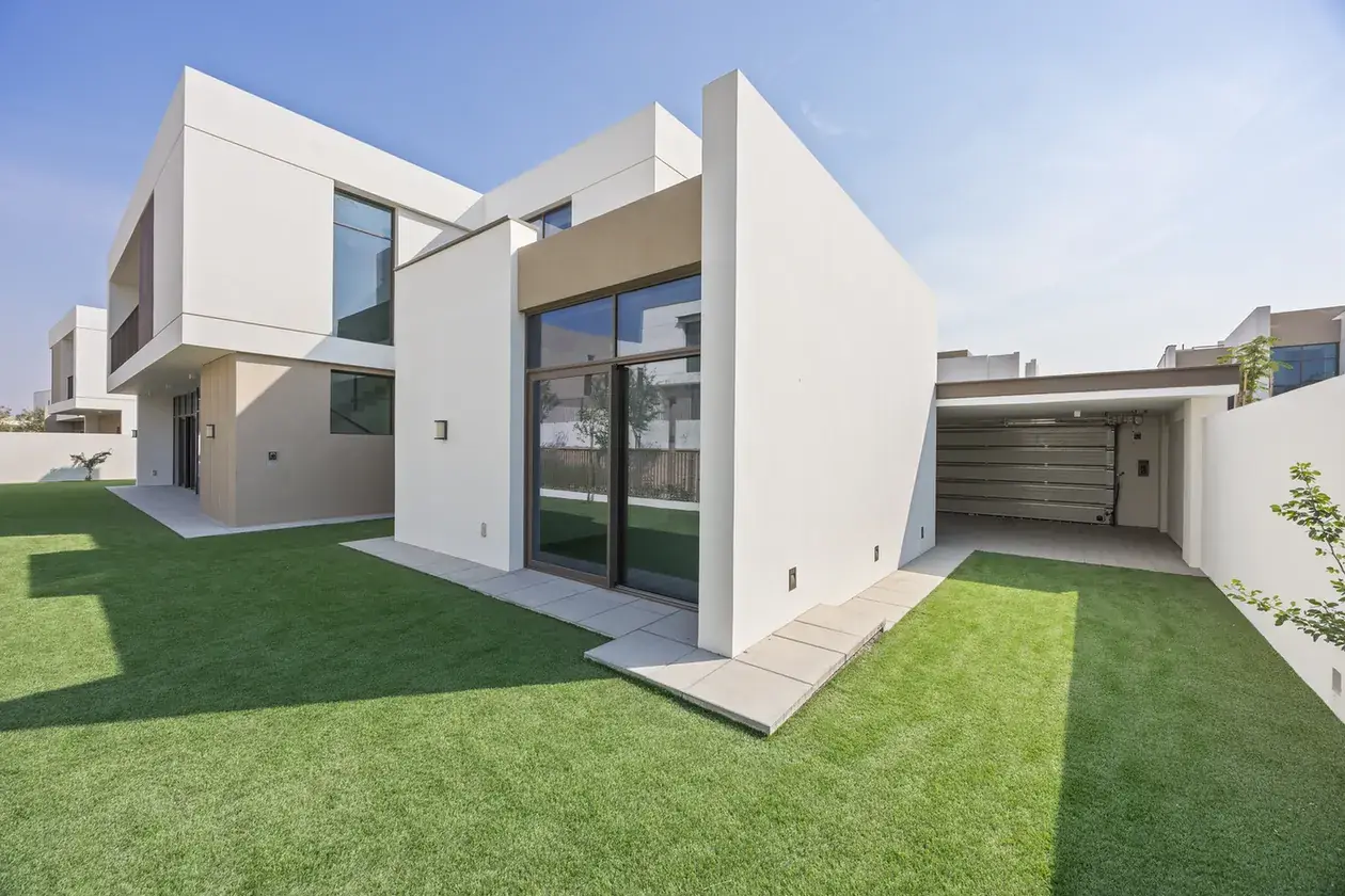 Side view of the villa from the landscaped garden with lawn and paved path. Villa photography by MRPS in Dubai for ELITE Property Brokerage.