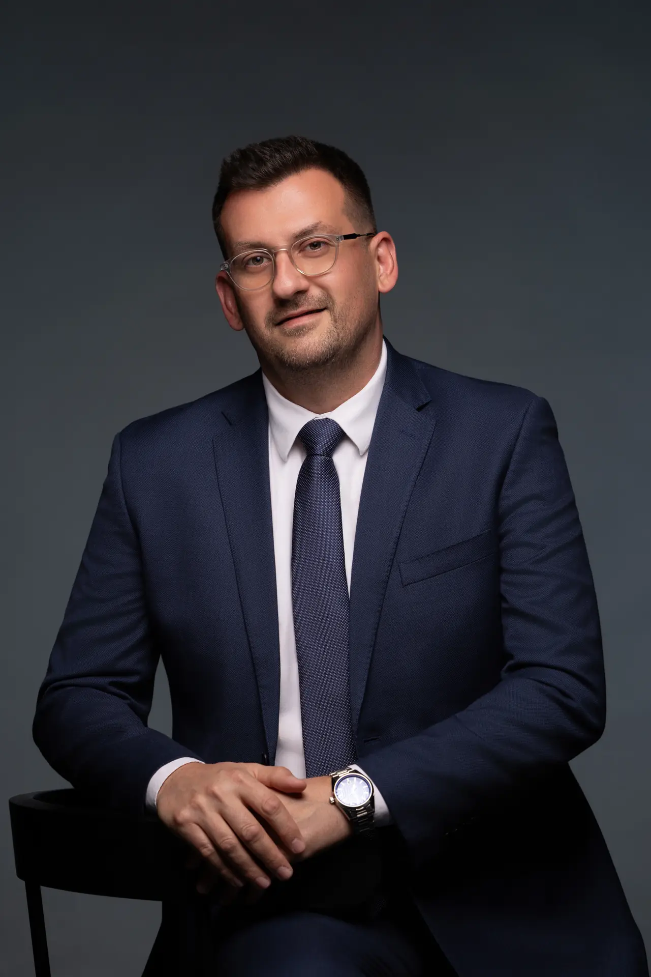 Seated executive portrait with hands together, relaxed and confident. Photographed at the MRPS studio in Business Bay, Dubai.