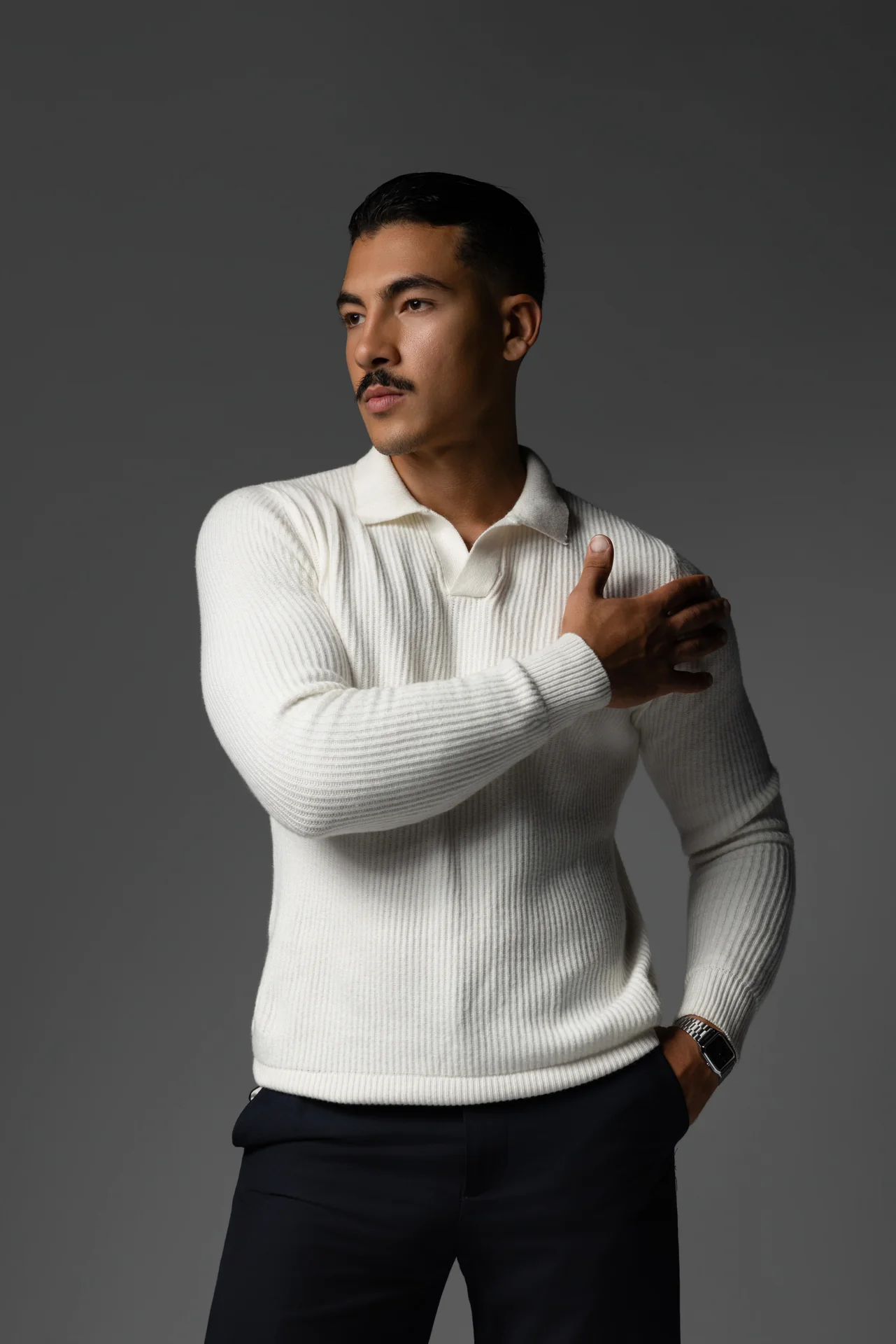 Three quarter portrait in a cream knit polo with one hand on the chest. Male modeling portfolio photoshoot by MRPS in Dubai, photographed by Nastaran.
