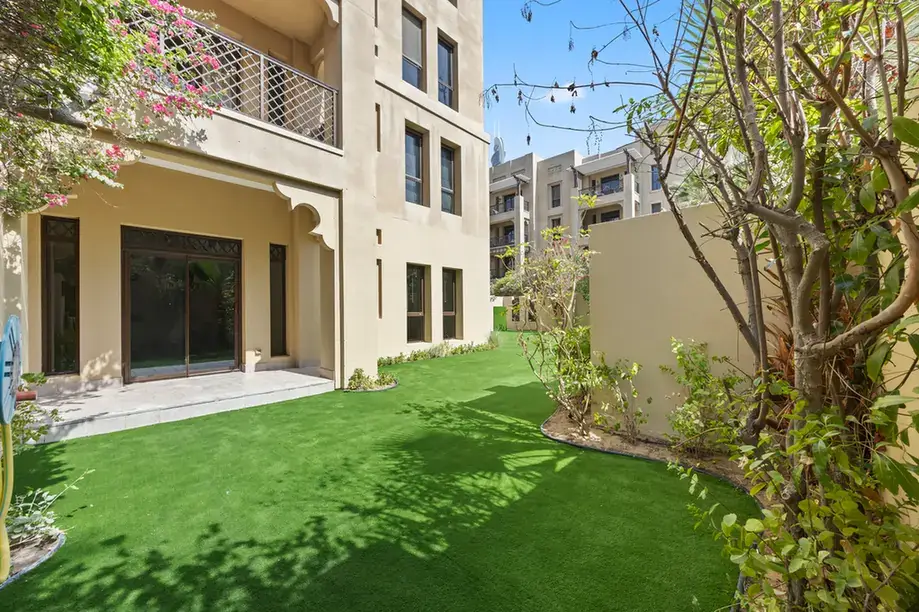 Private garden with bougainvillea and the shaded terrace in an unfurnished two-bedroom garden apartment in Old Town, Downtown Dubai, photographed for ELITE Property Brokerage.