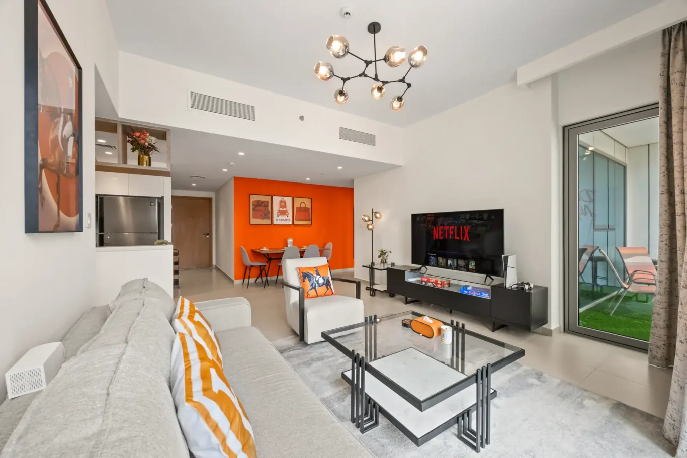 Wide view of the living room with black chandelier, grey sofa and dining area. Day, twilight and night Airbnb photography by MRPS for Vista Haus Holiday Homes in Downtown Dubai.