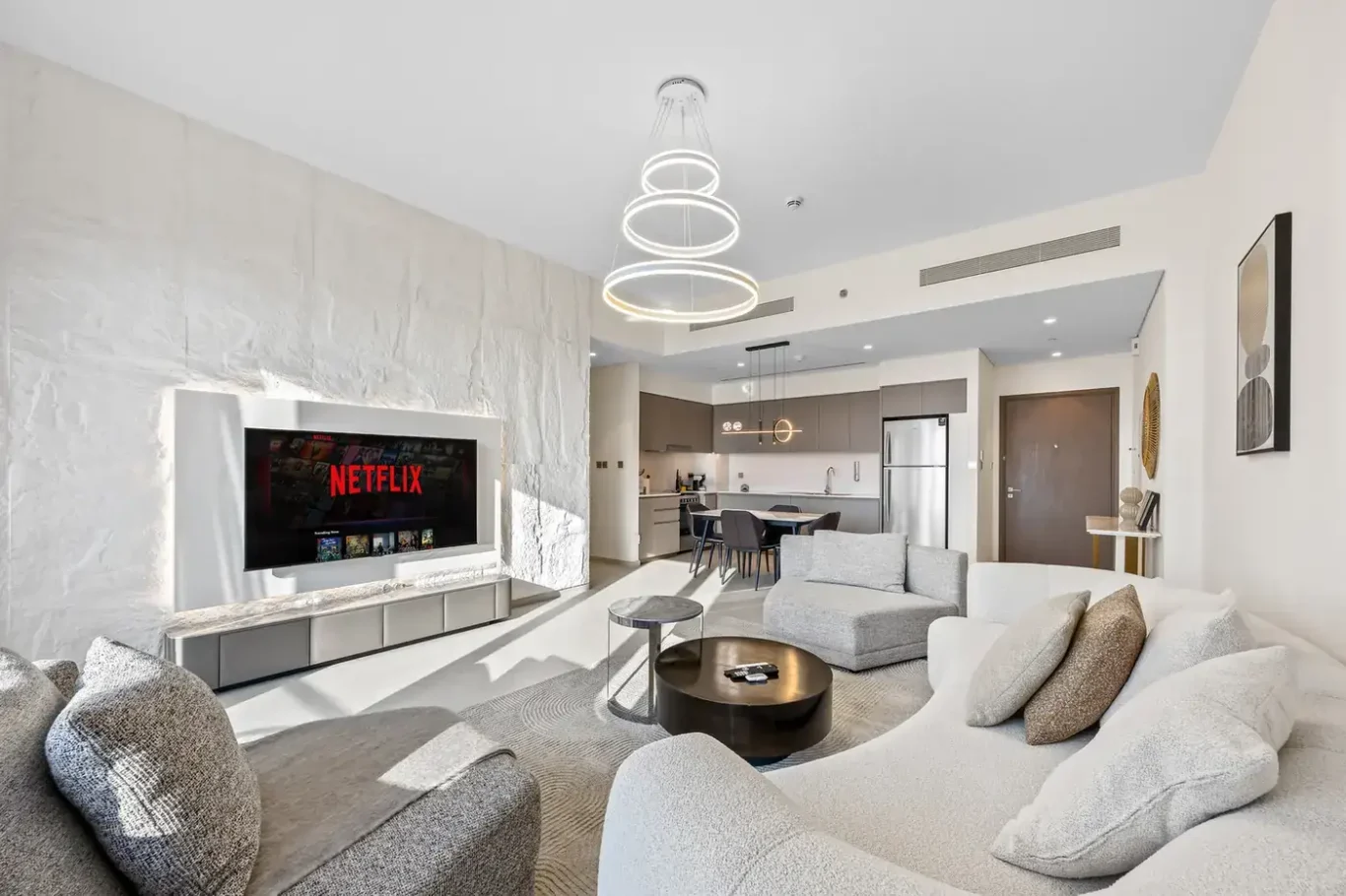 Living room with textured TV wall, curved sofa and modern chandelier. Airbnb photography by MRPS for Solea Stay in Dubai.