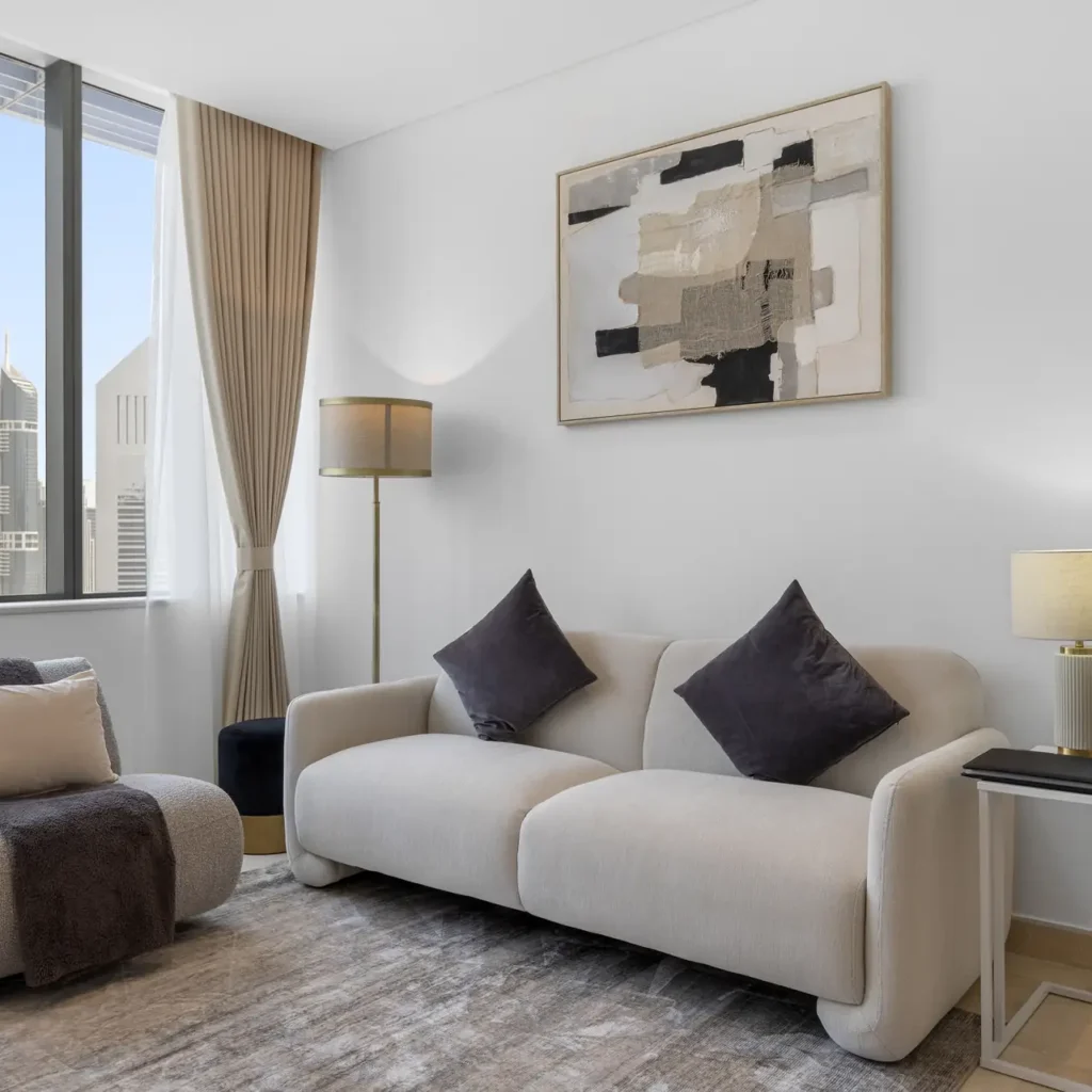 Sofa and armchairs with abstract artwork in a Your Stay Apartments one-bedroom at Sky Gardens, DIFC, Dubai.