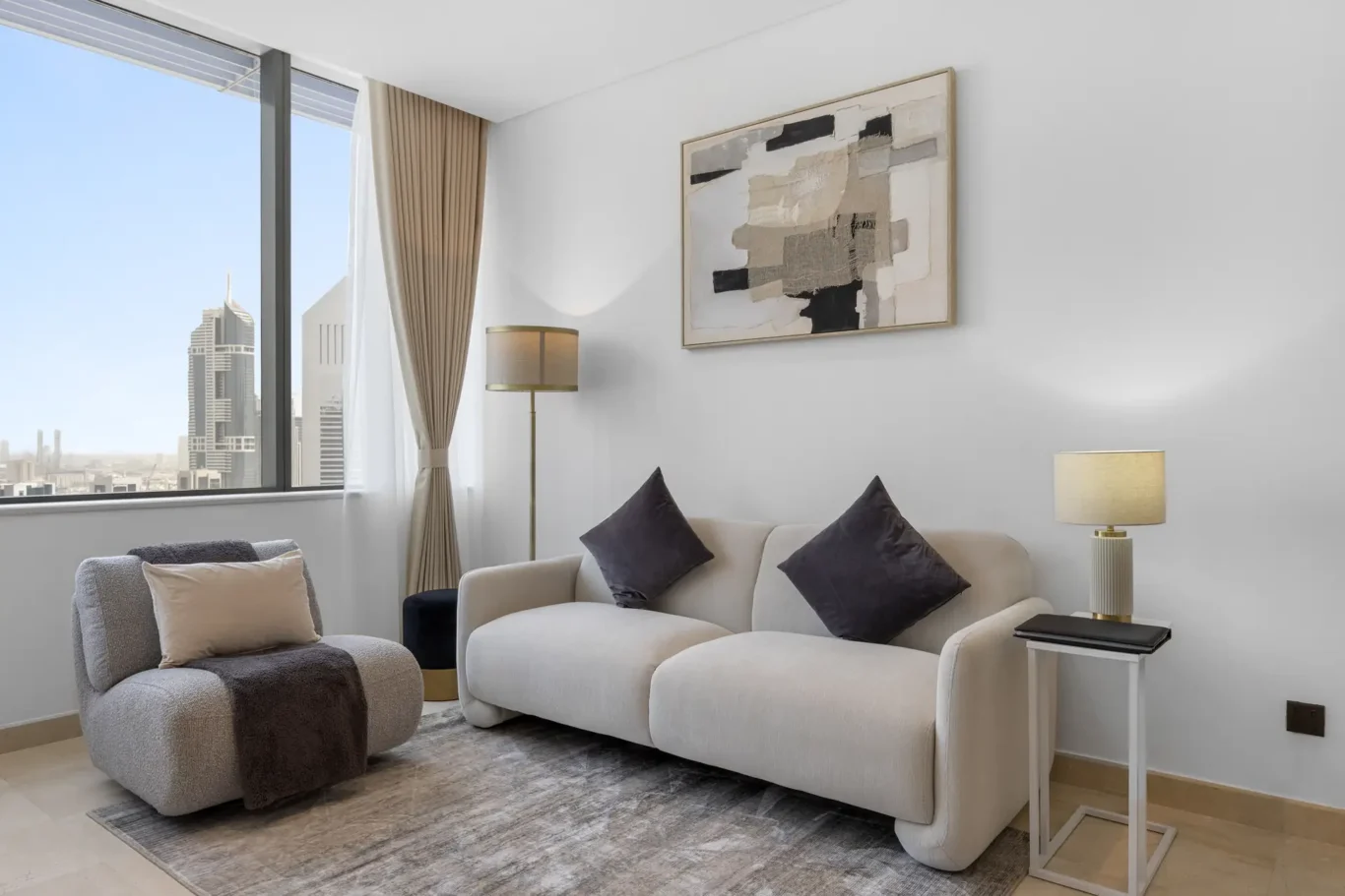 Sofa and armchairs with abstract artwork in a Your Stay Apartments one-bedroom at Sky Gardens, DIFC, Dubai.