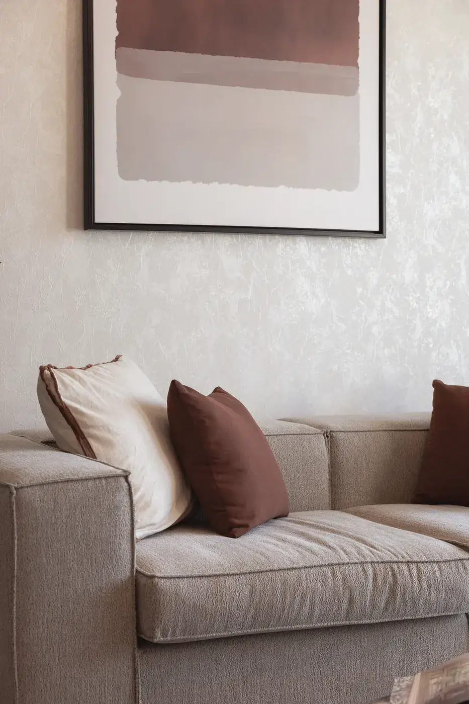 Linen sofa with cream and rust cushions under framed abstract art. Interior design photography for Aziza Home by MRPS in Dubai.