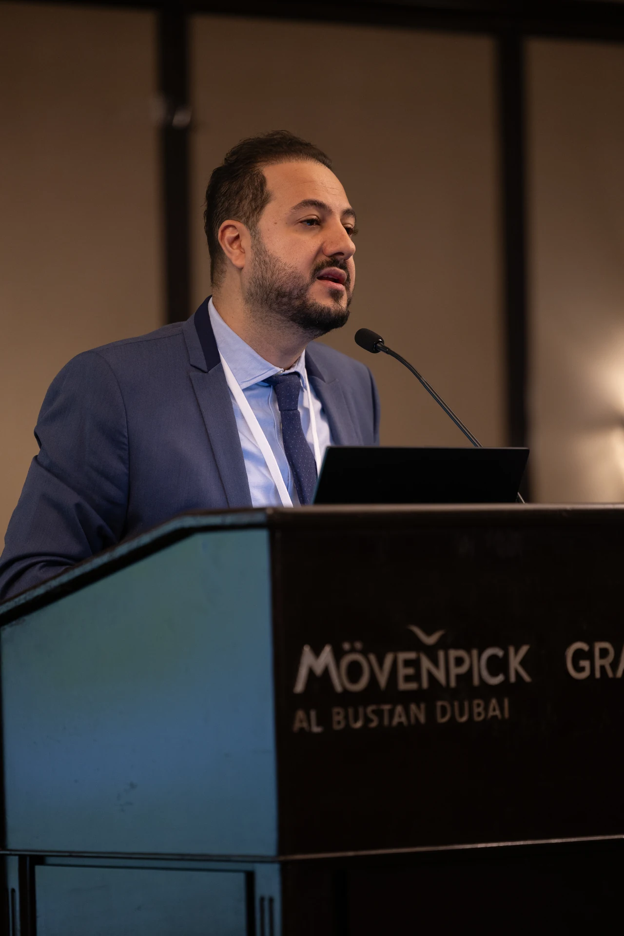 Speaker addressing the audience from the Movenpick Grand Al Bustan podium. Corporate event photography by MRPS for My Arabic Publishing at Movenpick Grand Al Bustan, Dubai.