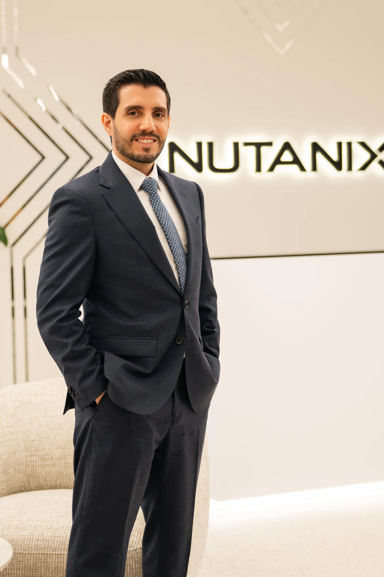Standing portrait in a dark suit at the office reception. On-site corporate headshot at the Nutanix office in Dubai.