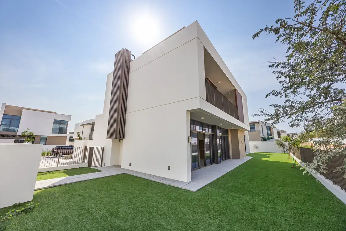 Rear exterior of the villa with lawn and covered terrace under a clear sky. Villa photography by MRPS in Dubai for ELITE Property Brokerage.