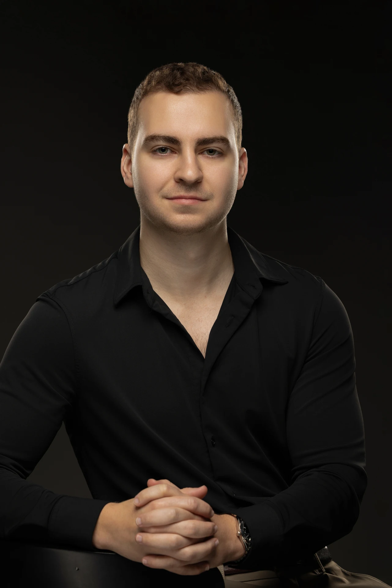 Seated portrait in a black shirt with hands together. Professional headshot of Tim Ruscica of Tech With Tim, photographed at the MRPS studio in Dubai.