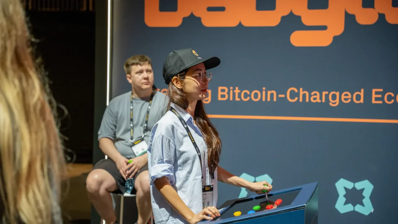 Visitors at the interactive game station in front of the Babylon wall. Photographed by MRPS for Eventflare at Binance Blockchain Week 2025, Coca-Cola Arena, Dubai.