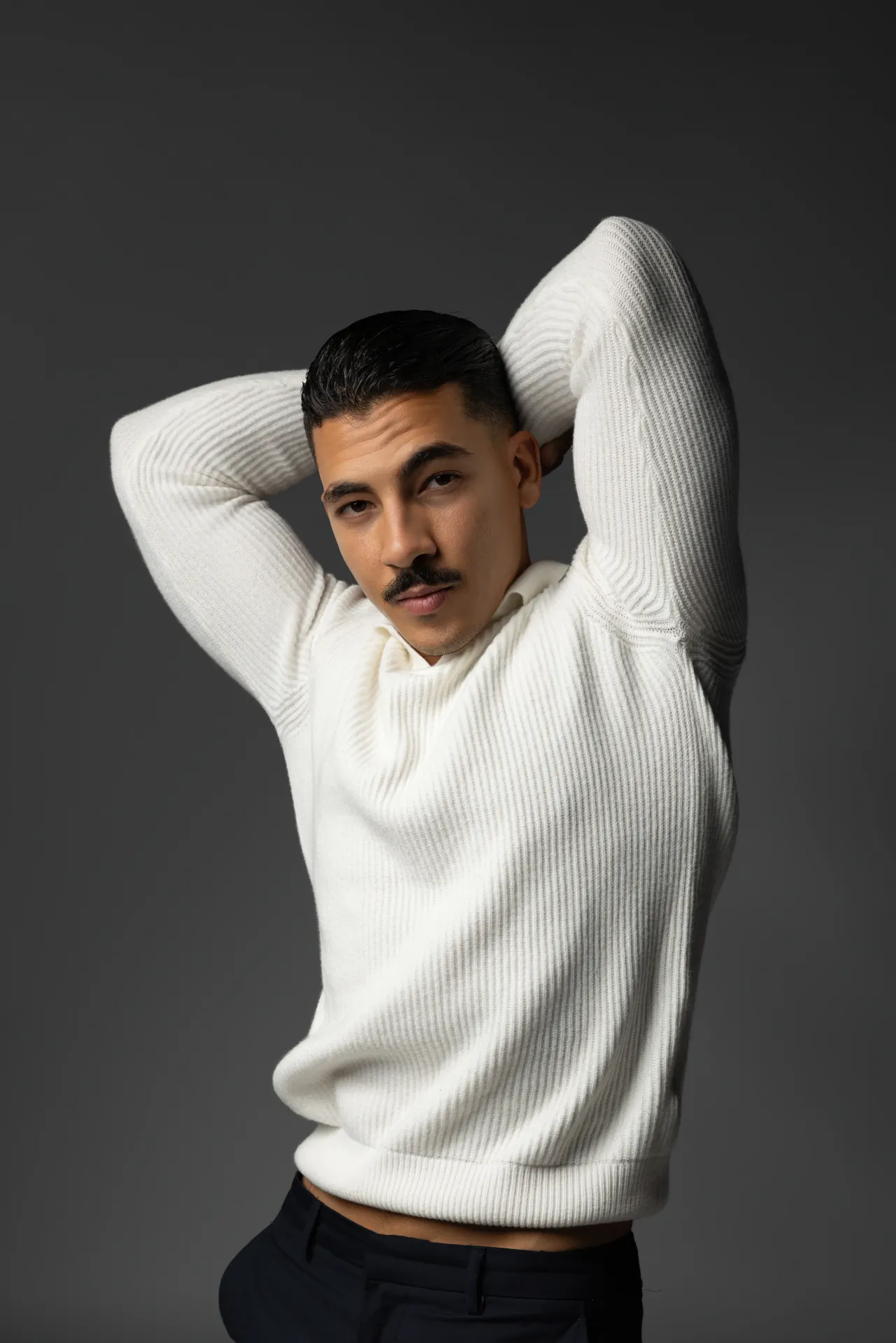 Relaxed portrait with hands behind the head in a cream knit sweater. Male modeling portfolio photoshoot by MRPS in Dubai, photographed by Nastaran.