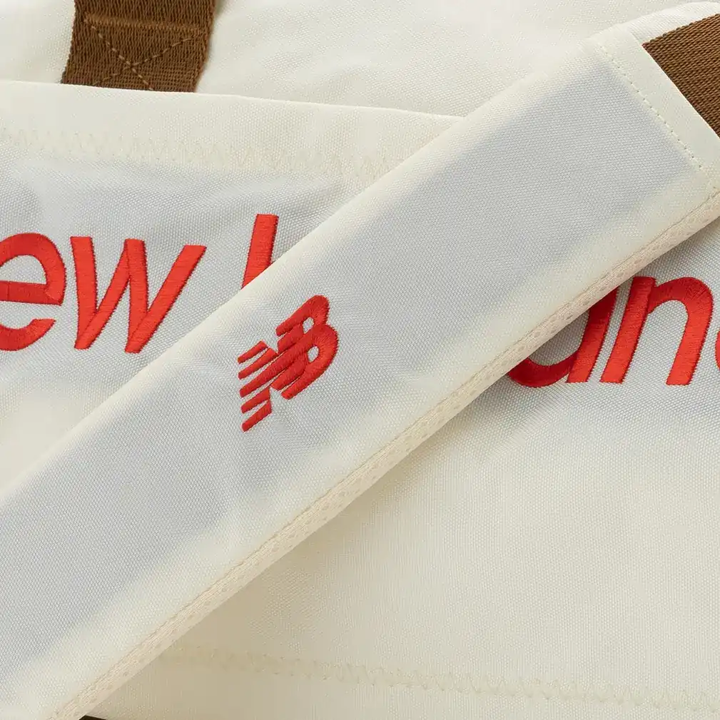 Close-up of the red New Balance logo and strap on the white duffel bag. E-commerce product photography for New Balance by MRPS in Dubai.
