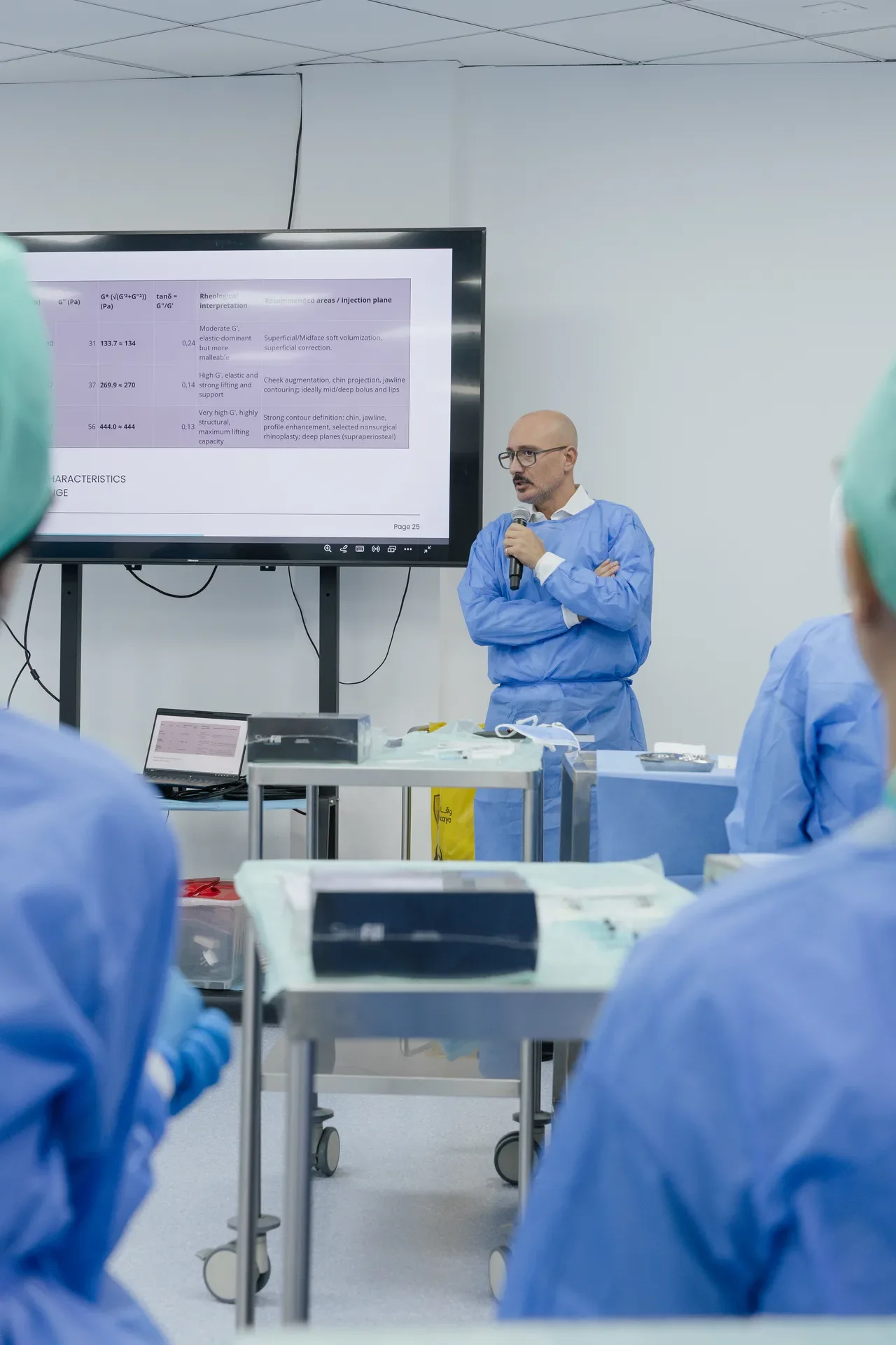 Instructor in scrubs presenting beside the lecture screen. Event photography by MRPS at the Promoitalia Cadaver Lab medical anatomy course in Dubai.