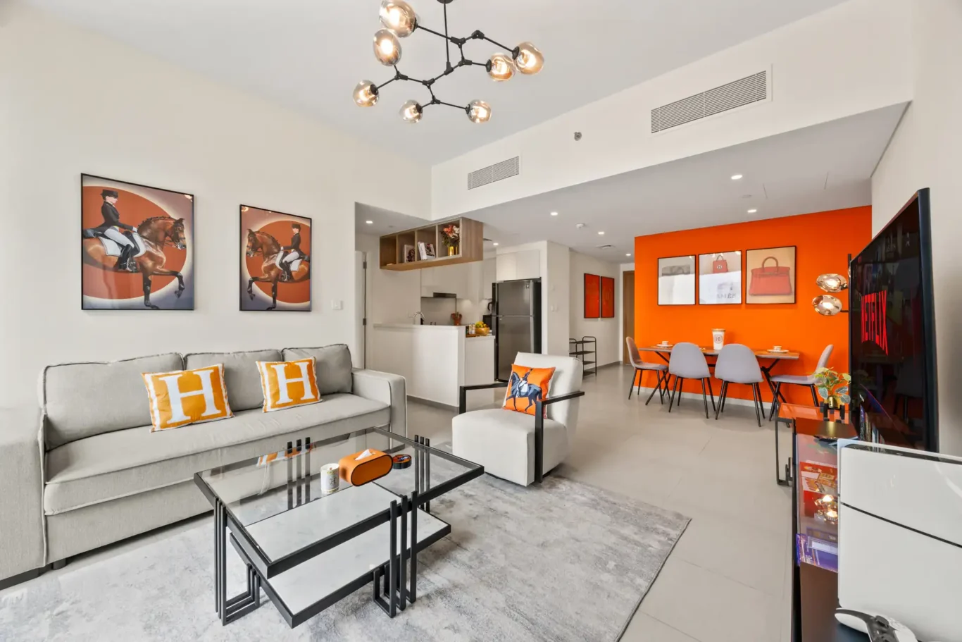 Living room with grey sofas and an orange feature wall in the two bedroom apartment. Day, twilight and night Airbnb photography by MRPS for Vista Haus Holiday Homes in Downtown Dubai.