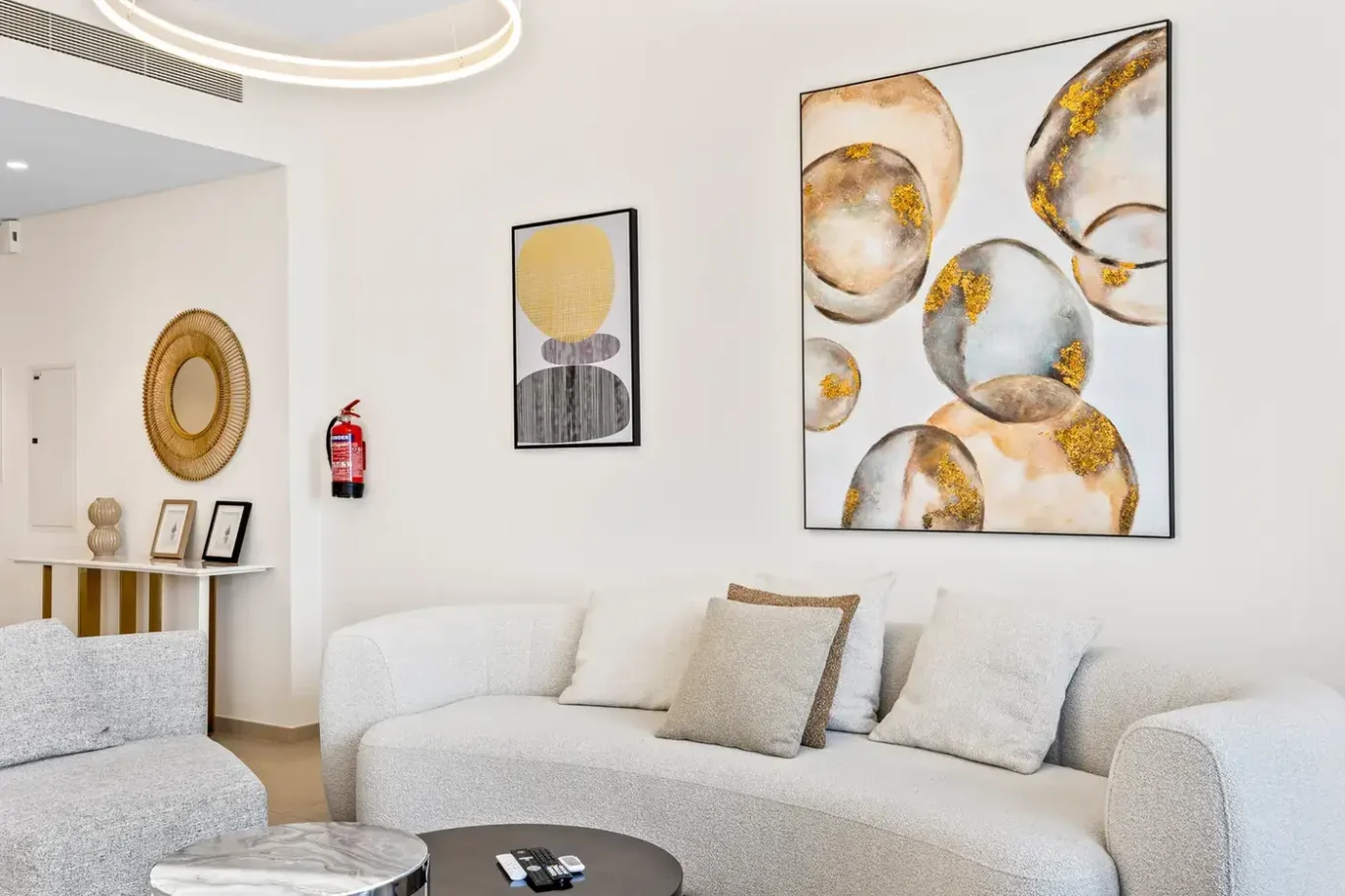 Curved white sofa with gold abstract wall art in the living room. Airbnb photography by MRPS for Solea Stay in Dubai.