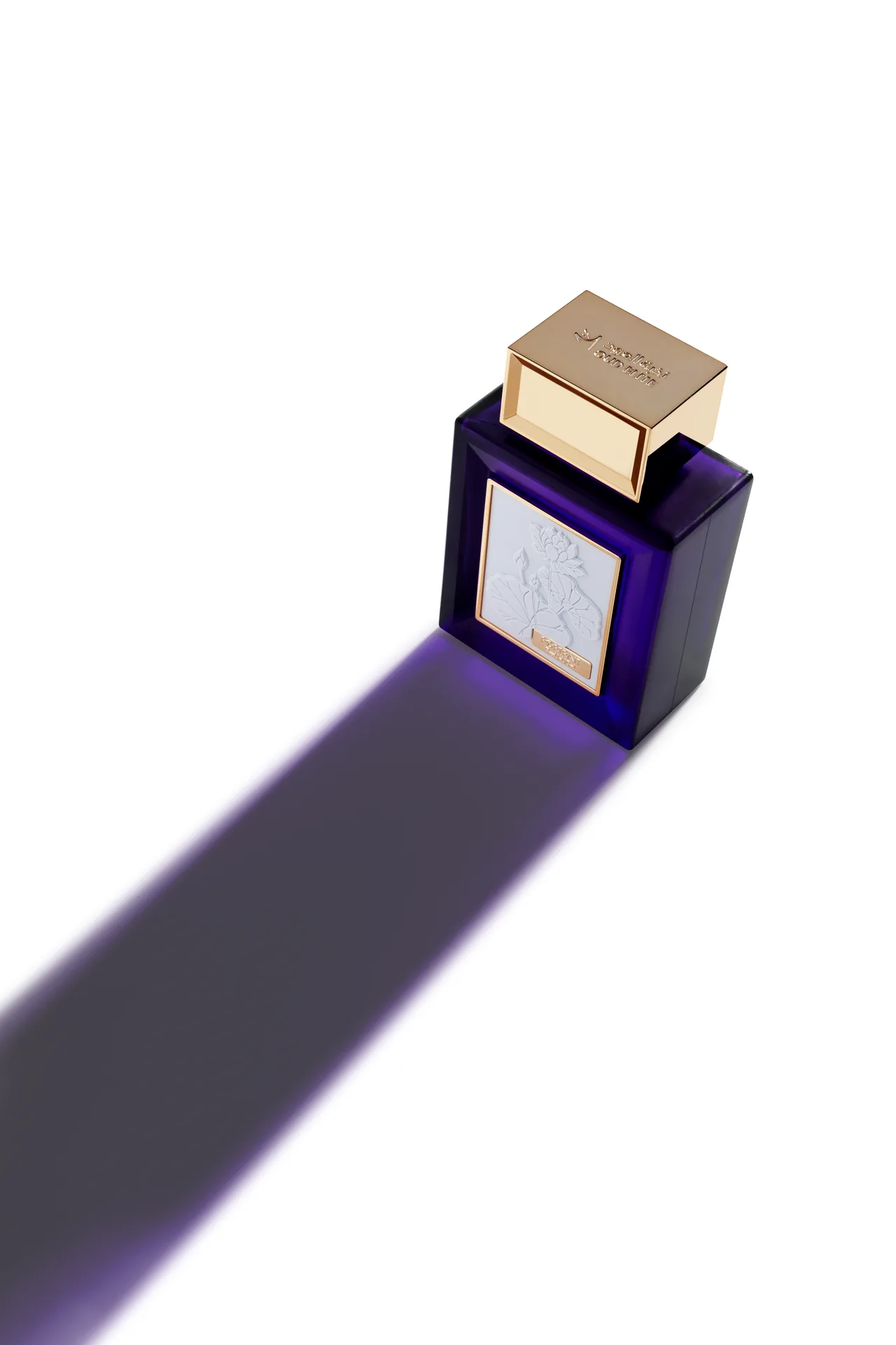 High-angle shot of the blue Oud Elite Portrait perfume bottle casting a long violet shadow across a white surface.