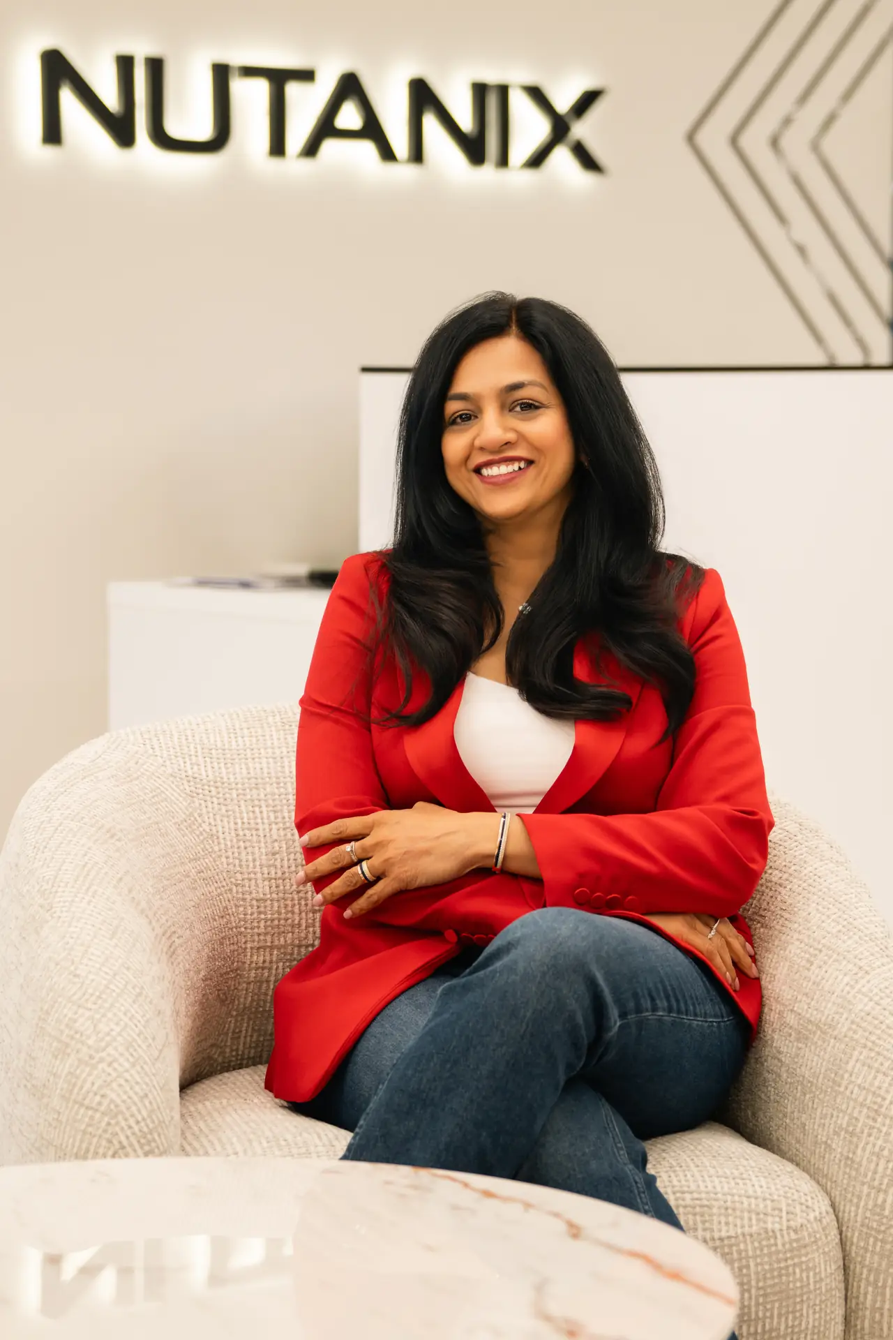 Team member in a red blazer seated in a lounge chair in the office. On-site corporate headshot at the Nutanix office in Dubai.