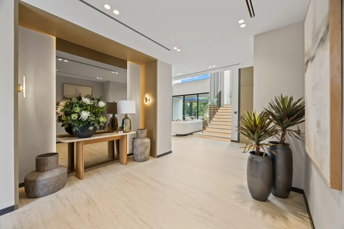 Entrance console with flowers and large vases, looking through to the living room, luxury villa in Jumeirah Islands, Dubai.