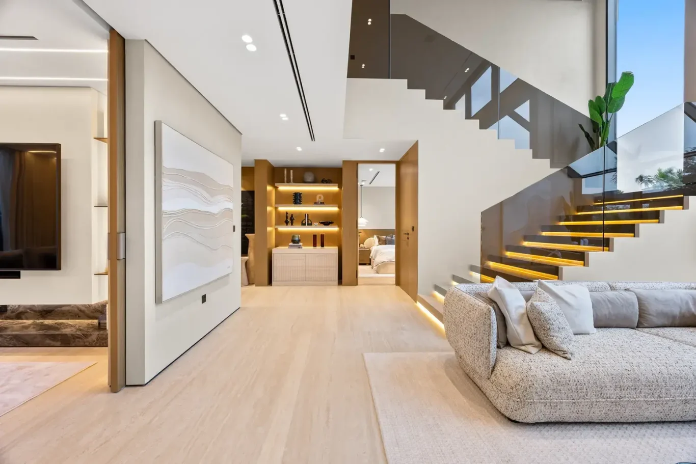Living area with a curved sofa and a floating staircase, luxury villa in Jumeirah Islands, Dubai.