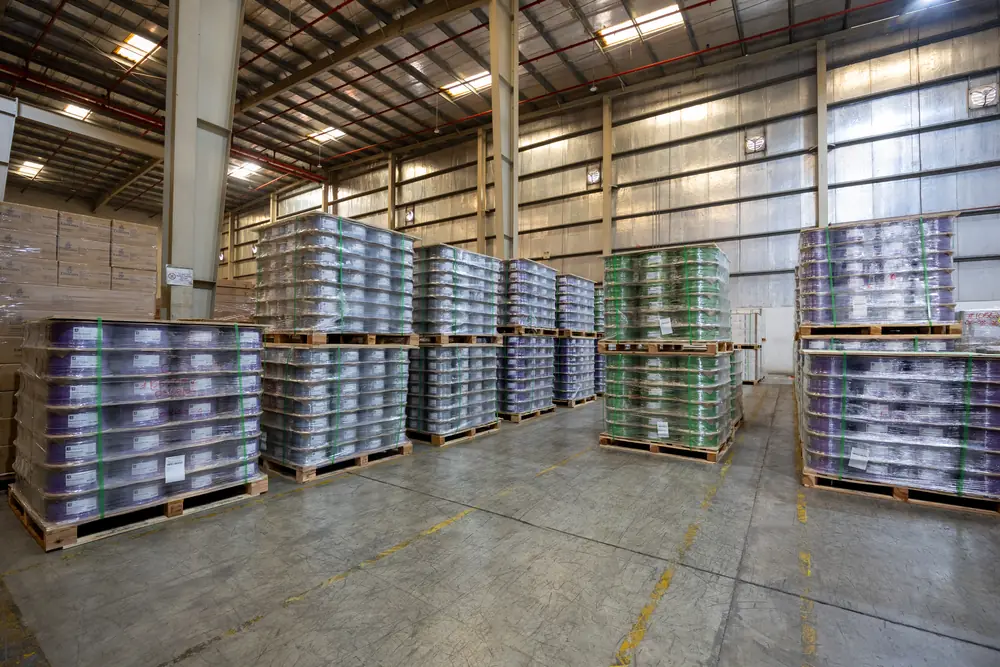 Rows of palletised cable reels in purple, grey and green wrapped for dispatch at the B3 International warehouse.