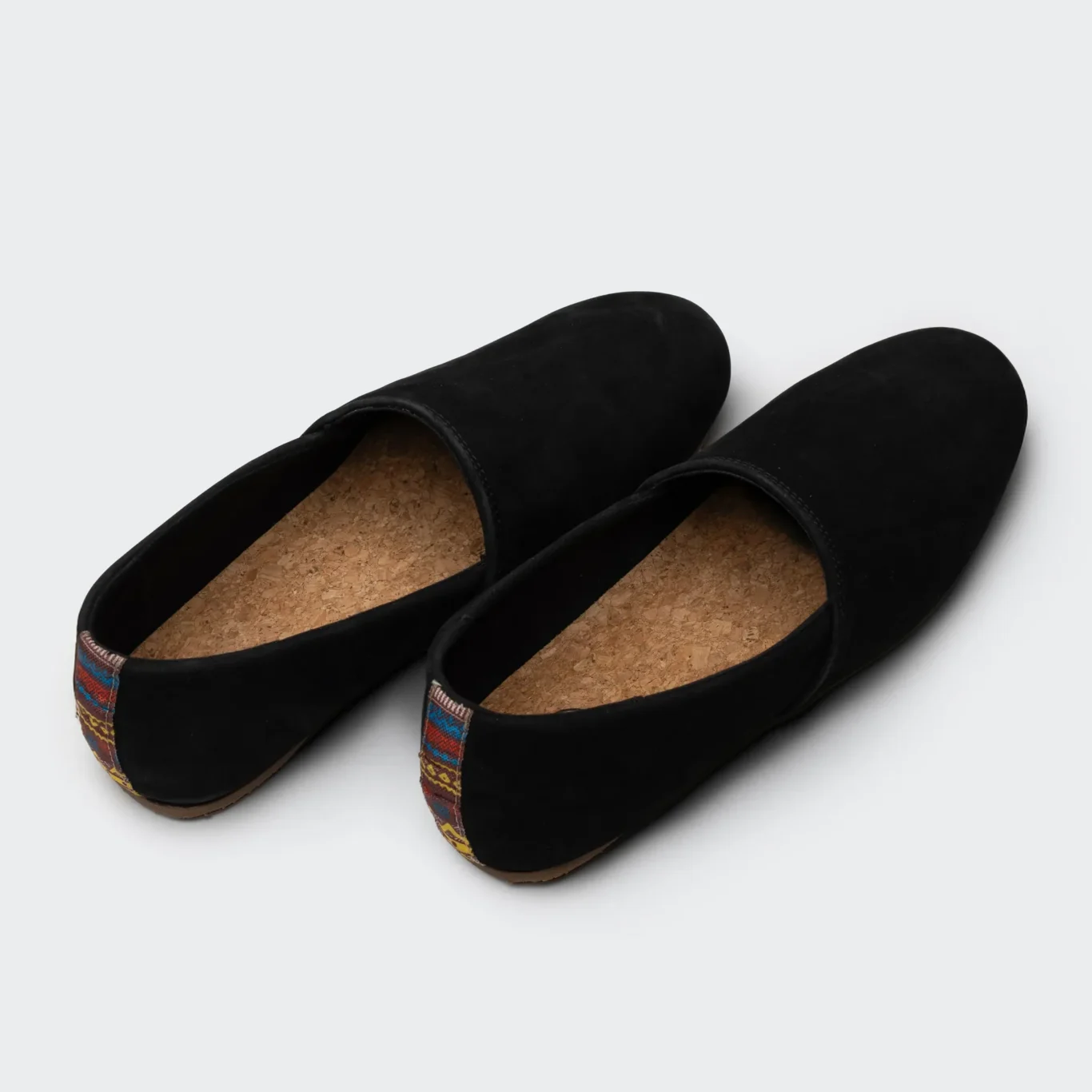 Pair of black SWAVE slip-ons from behind with cork insoles. E-commerce shoe photography for SWAVE by MRPS in Dubai.