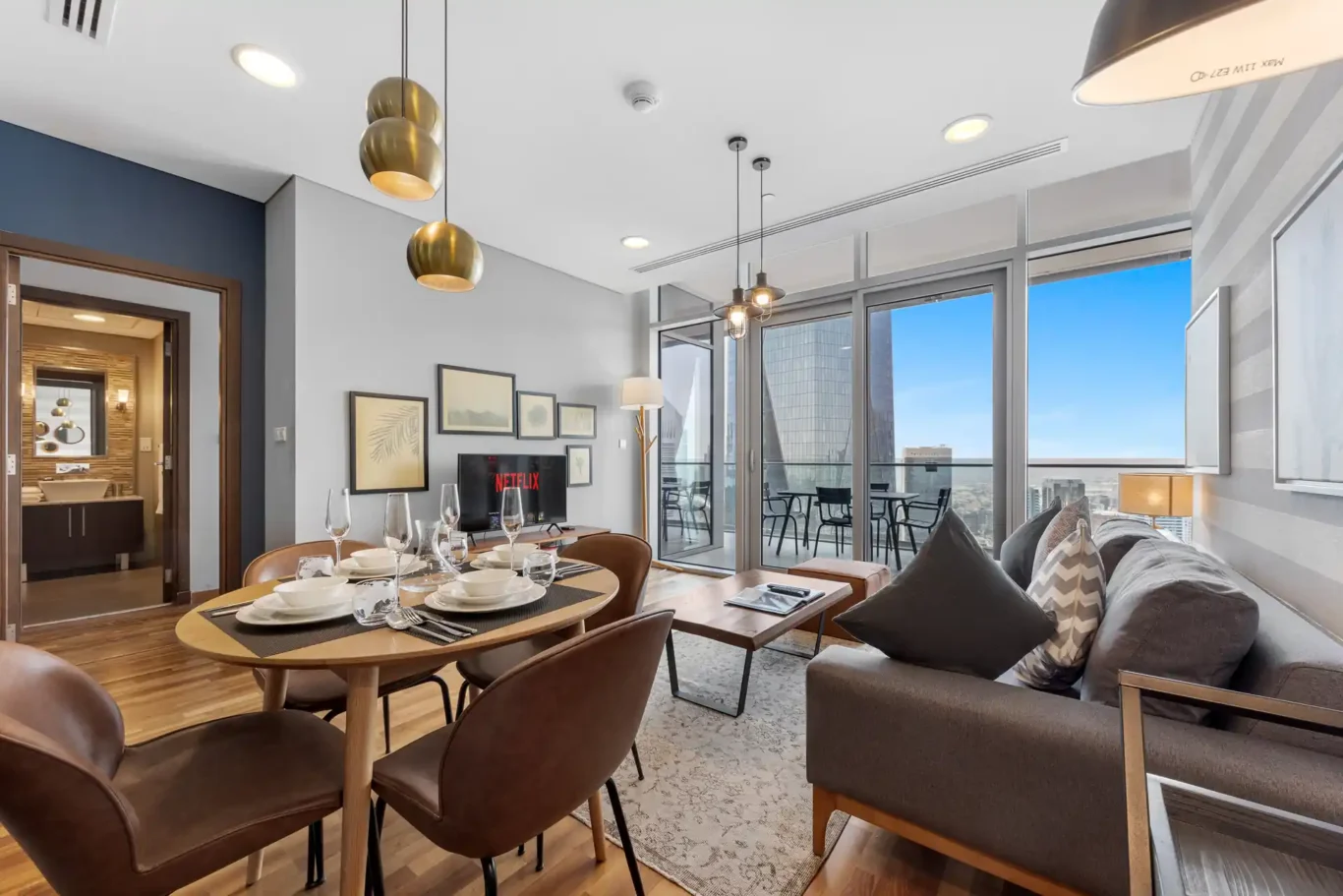Dining table and living area beside the windows in a Your Stay Apartments one-bedroom at Burj Daman, DIFC, Dubai.