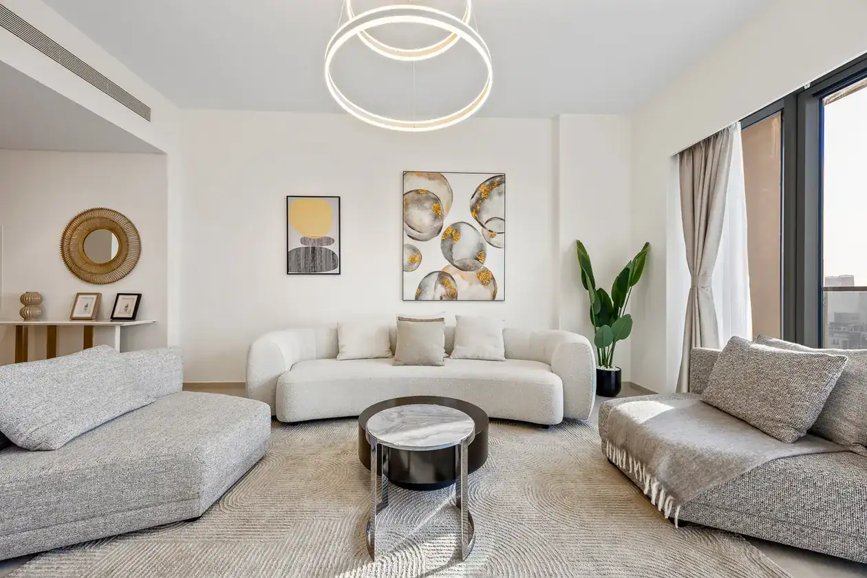 Living room with round coffee table, boucle armchairs and a statement chandelier. Airbnb photography by MRPS for Solea Stay in Dubai.