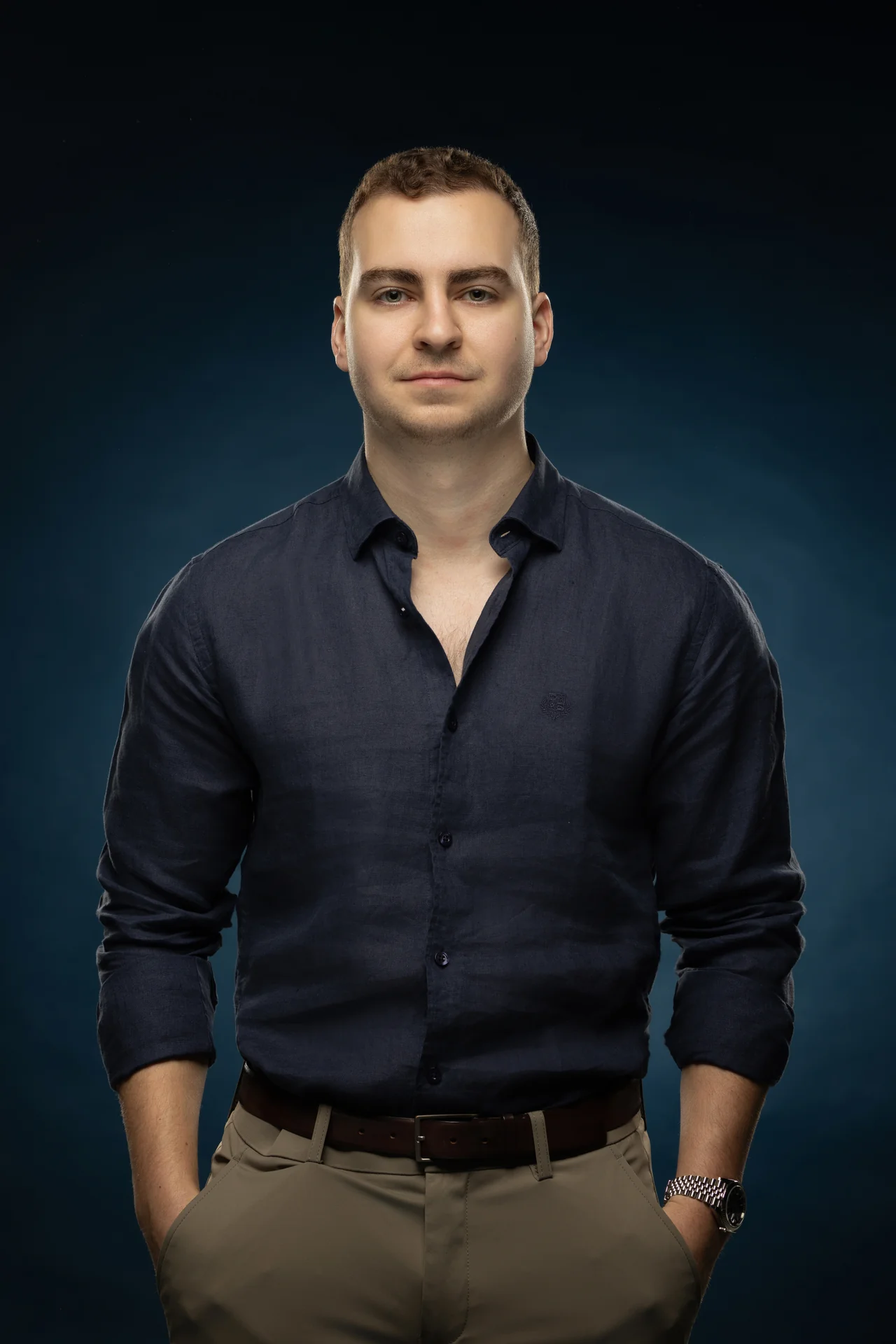 Standing portrait in a navy shirt on a deep blue backdrop. Professional headshot of Tim Ruscica of Tech With Tim, photographed at the MRPS studio in Dubai.